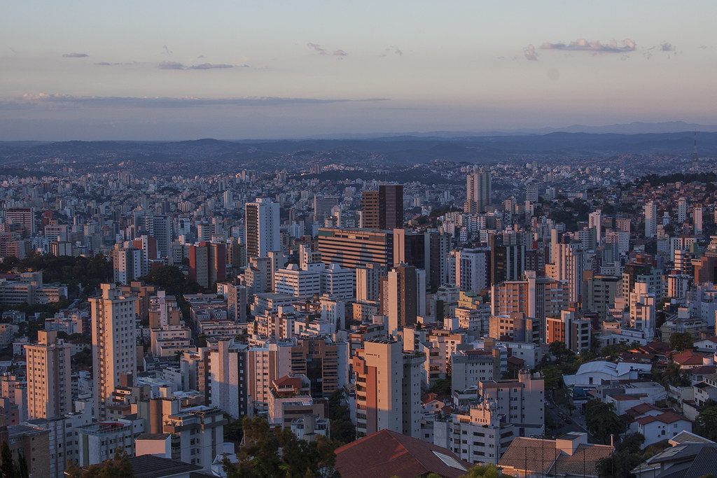 Vista panorâmica de Belo Horizonte ao entardecer com céu limpo e prédios iluminados pela luz do pôr do sol
