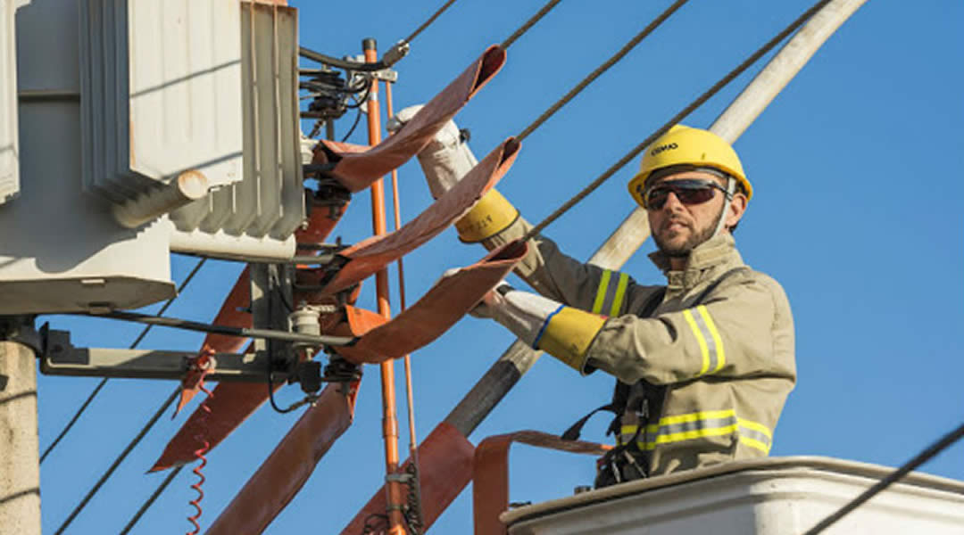 Técnico da Cemig realiza manutenção em rede elétrica para combater ligações clandestinas de energia em Minas Gerais.
